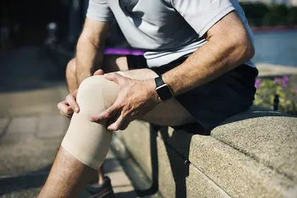 man holding his knee due to knee pain