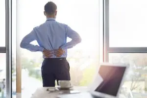 young business man holding his lower back due to pain