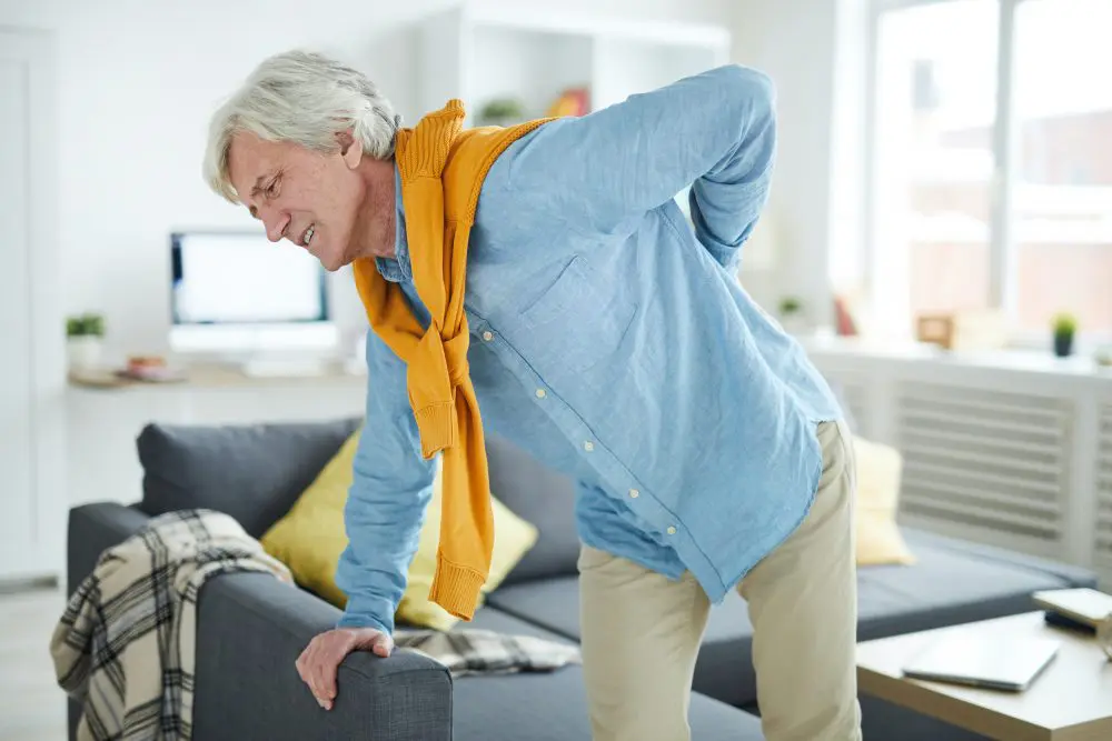 elderly man having back pain getting out of the chair