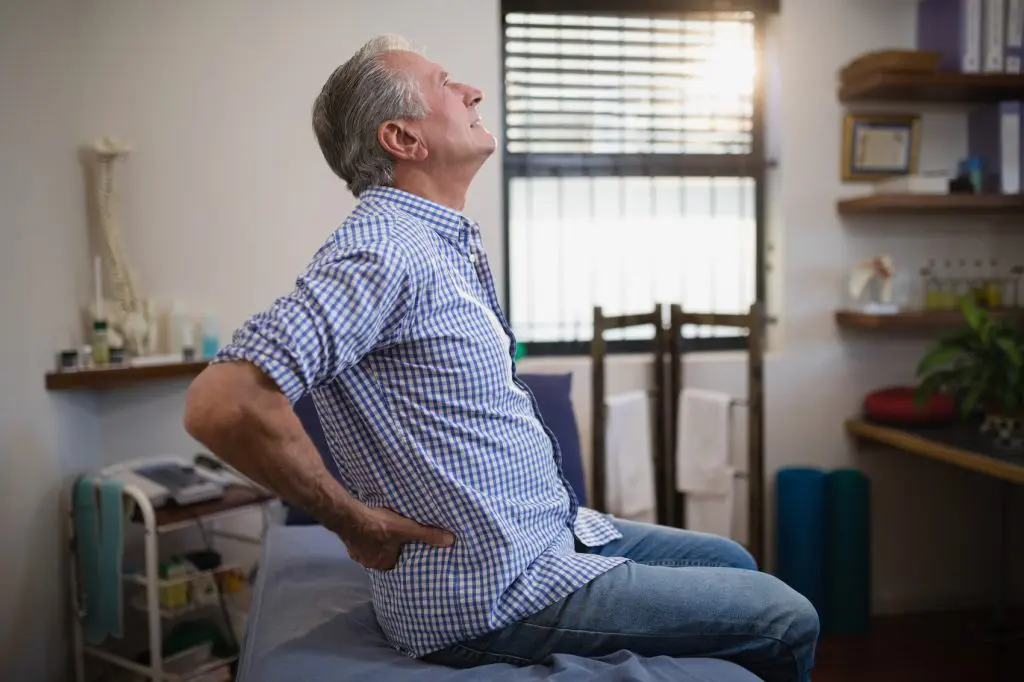 Elderly man holding his lower back and hips due to pain