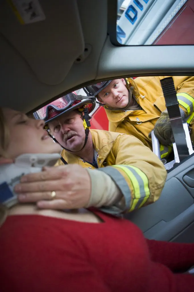 Firefighters helping an injured woman in a car