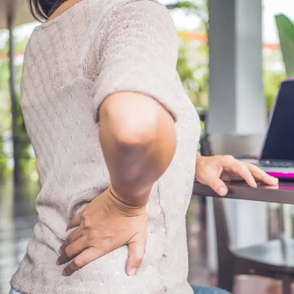 cropped image of a woman experiencing hip pain while working