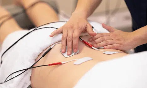 chiropractor using an electrical muscle stimulator on a patient