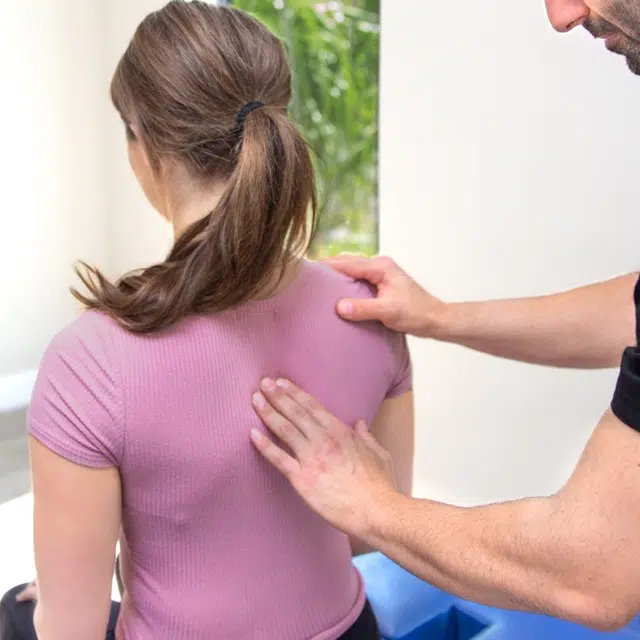 chiropractor pressing a female patient's middle back