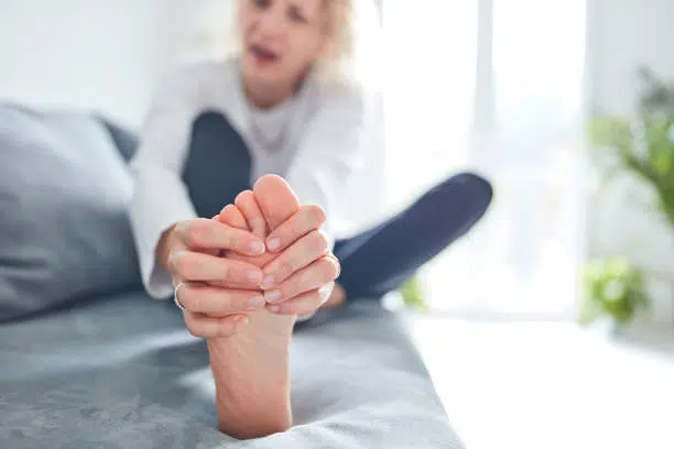 Woman is doing some stretching and massage to lessen her leg pain