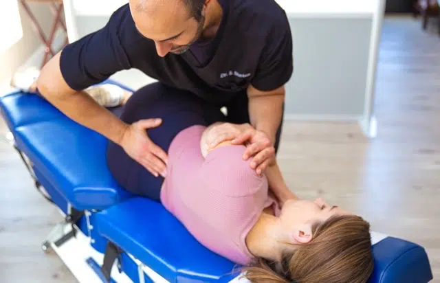 male chiropactor adjusting a female patient's back while on a drop table