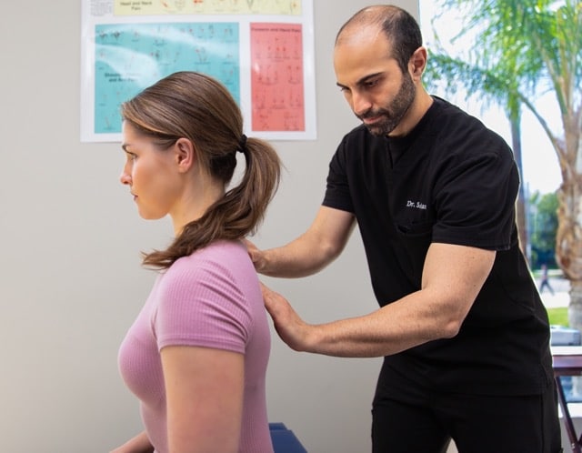 A chiropractor doing adjustments and manipulation on the back of the female patient to correct posture
