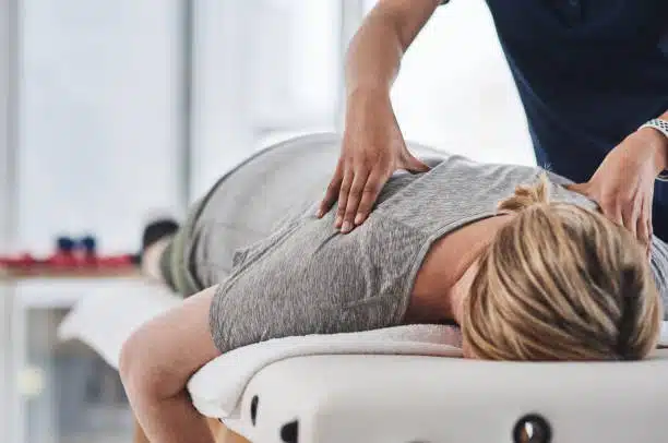 Shot of a mature woman lying face down and getting her back massaged by a physiotherapist at a clinic