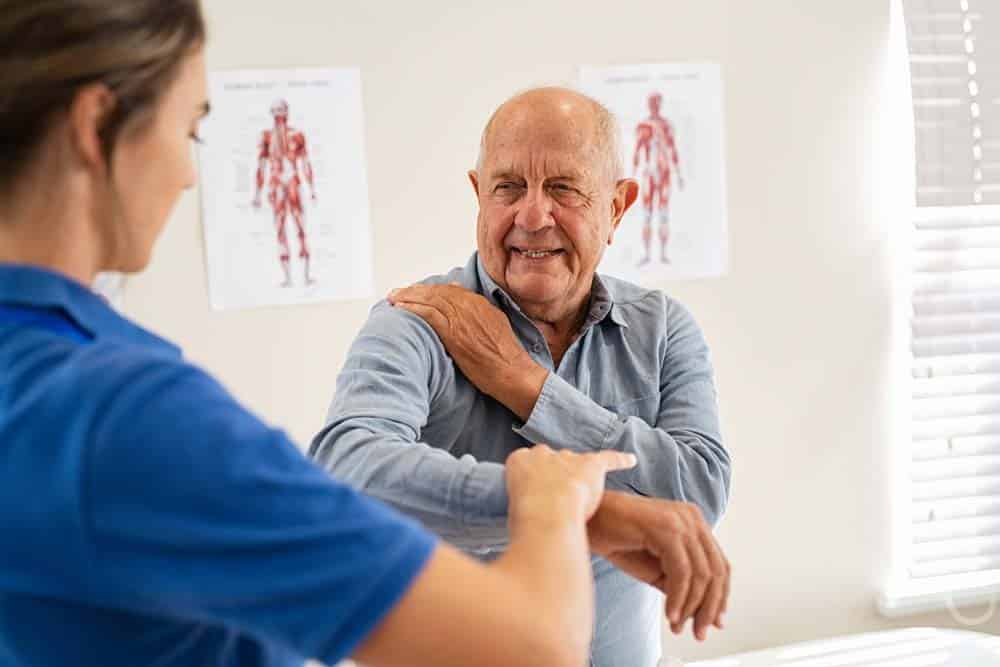 Chiropractor helping senior man while having a chiropractic evaluation.