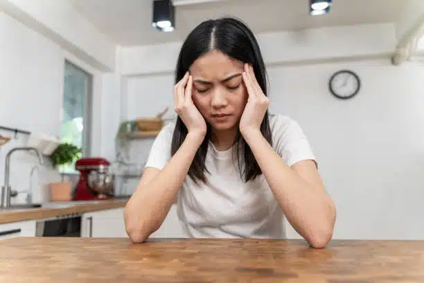 Woman suffers from headaches massaging her temples to relieve the pain.