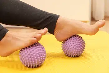 female feet  rolling on prickly massage balls