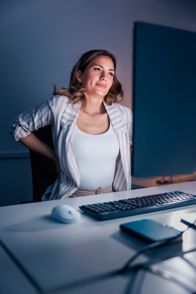 A woman stretching out at her desk while working