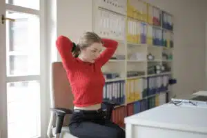 Female employee stretching while sitting