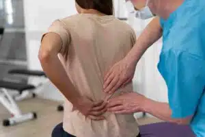 A physical therapist assesses a patient's lower back pain by using hands-on techniques in a clinical setting.
